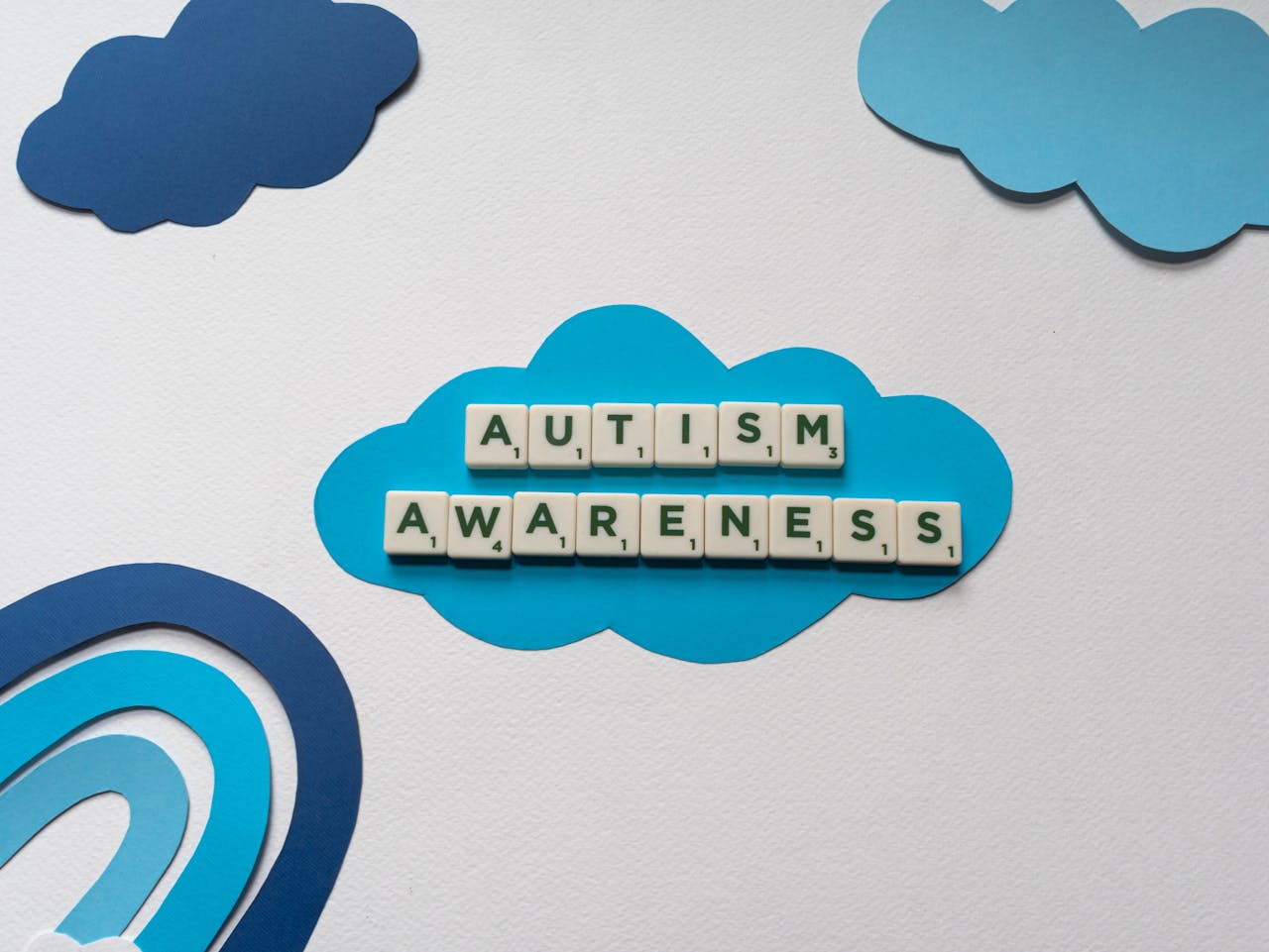 Creative autism awareness concept with Scrabble tiles on blue paper clouds.